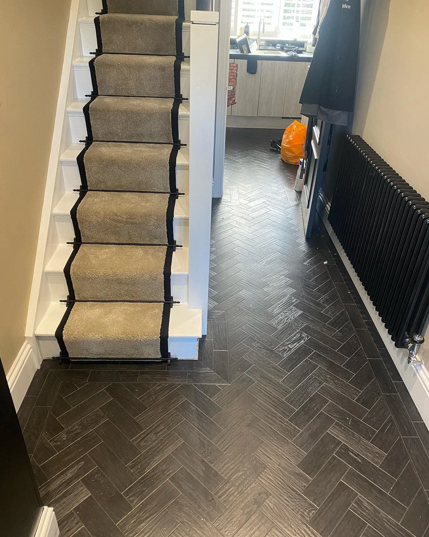 Bordered stair carpet above a herringbone hallway