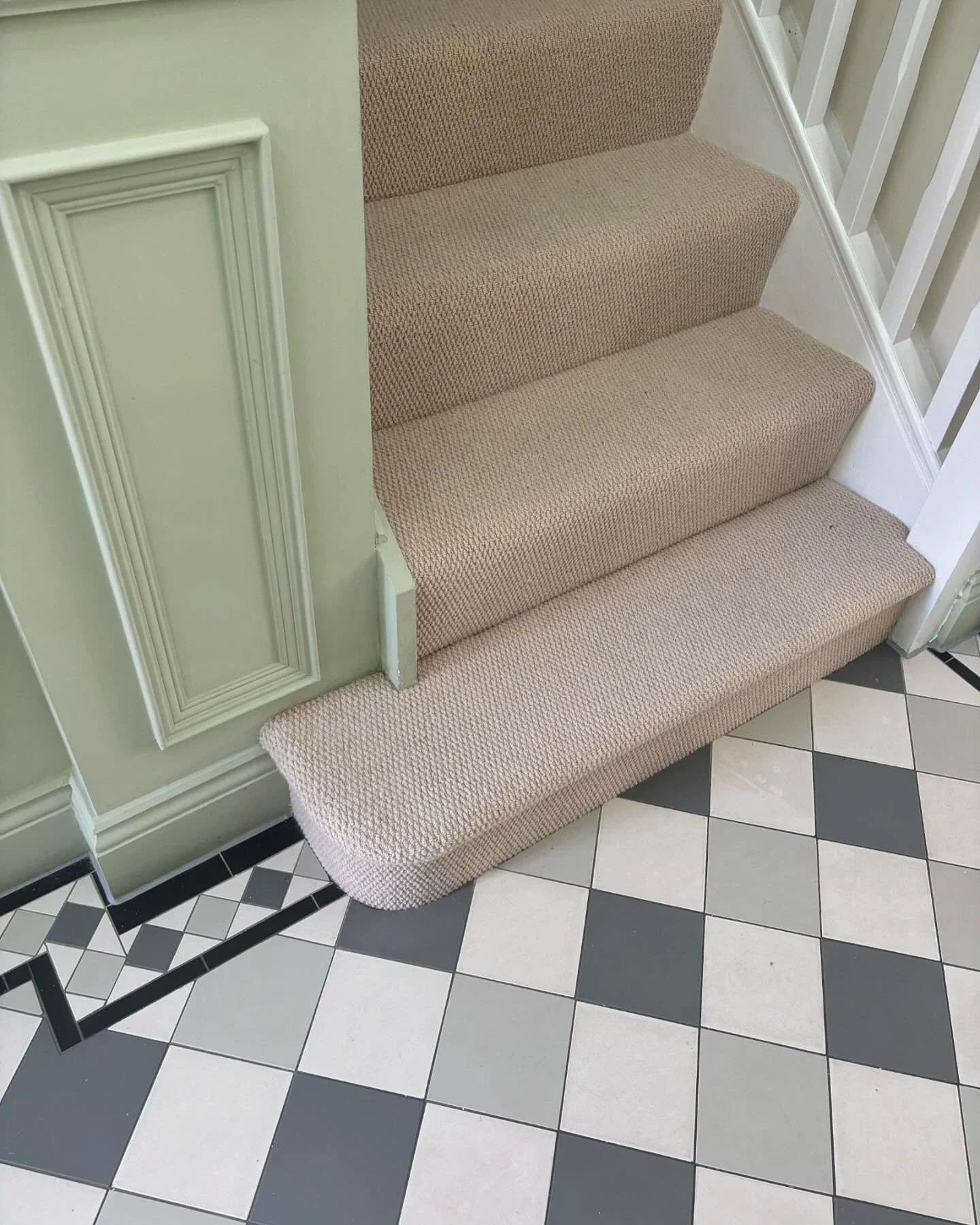 Beige carpet on stairs beside a patterned tiled hallway