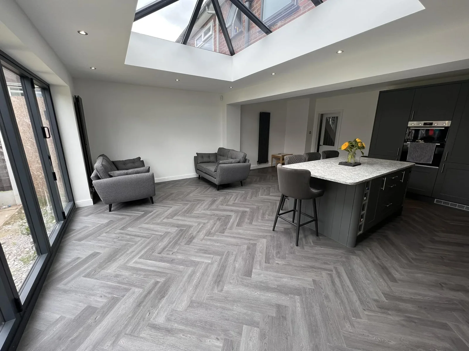 Grey herringbone flooring in an open-plan kitchen and living room