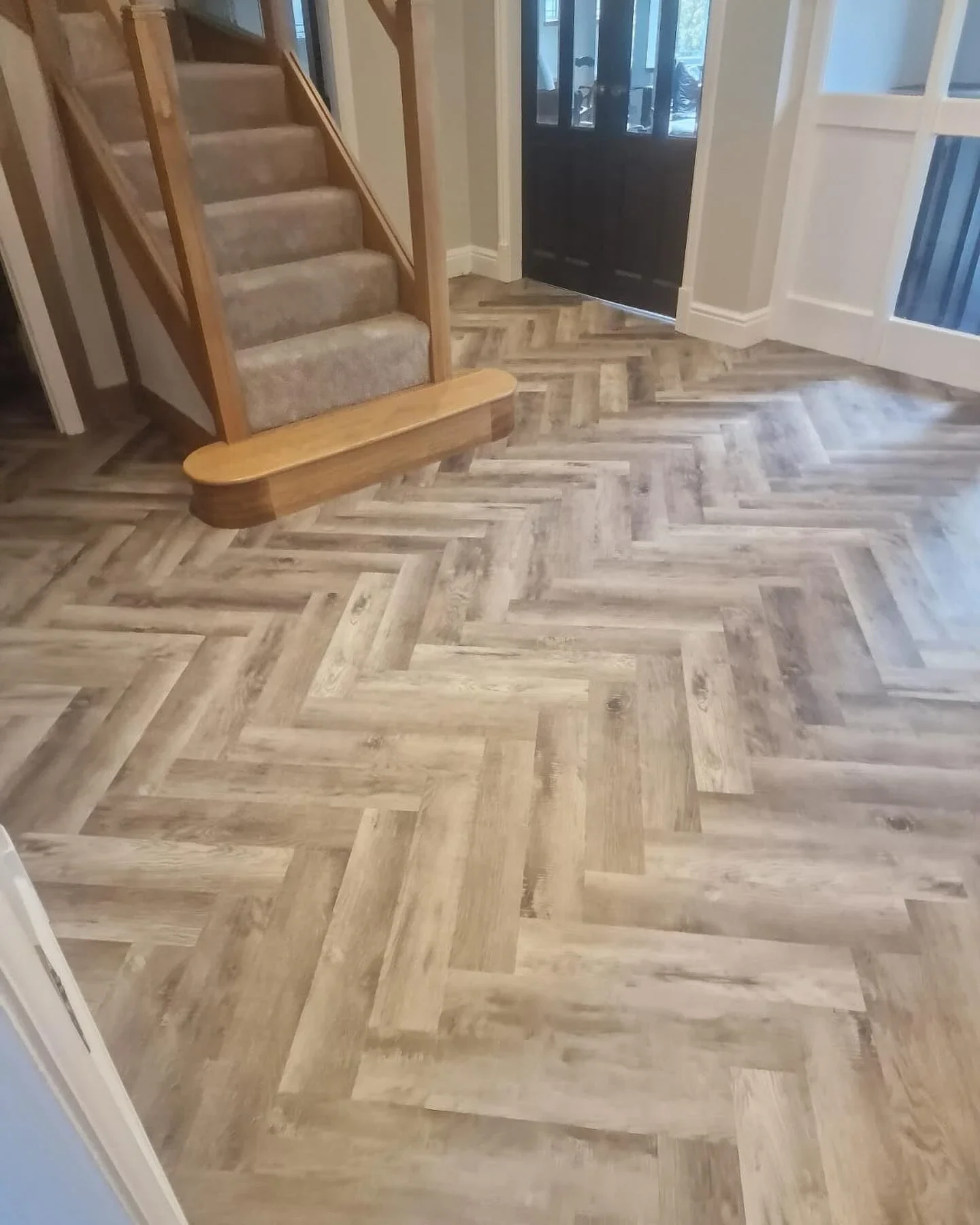 Herringbone hallway flooring beside a carpeted staircase