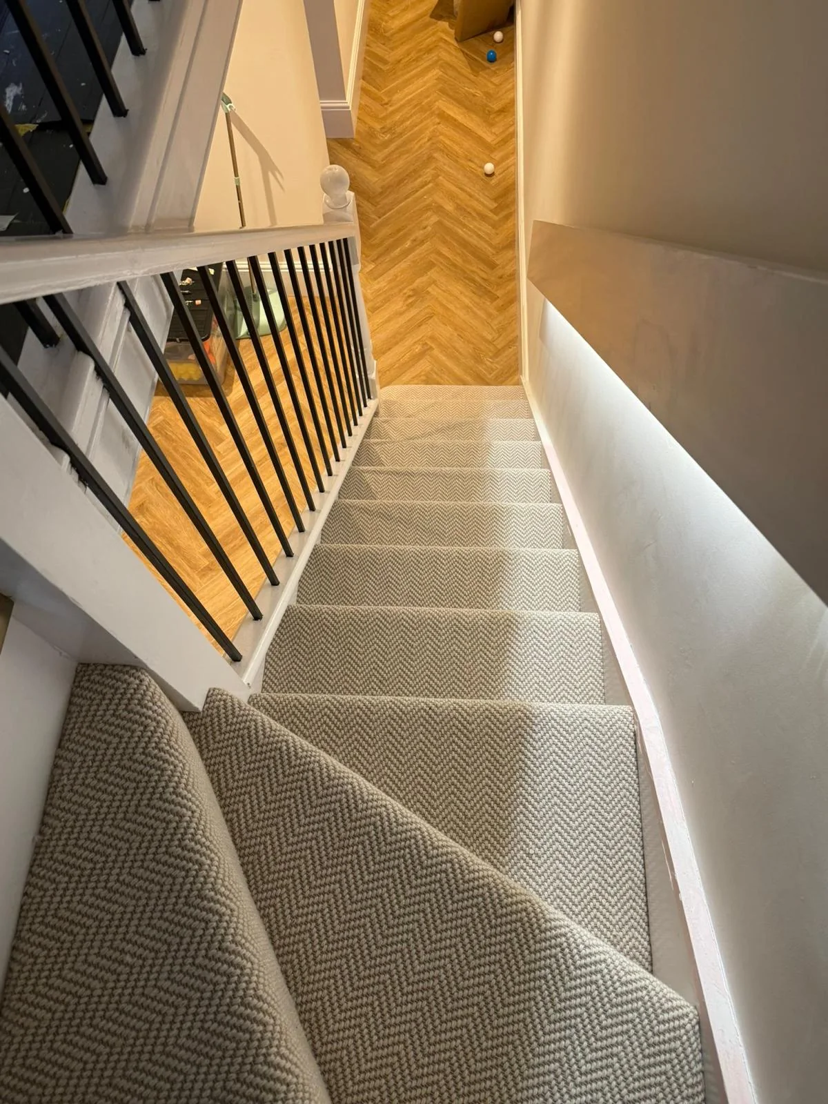 Carpeted staircase above a herringbone hallway