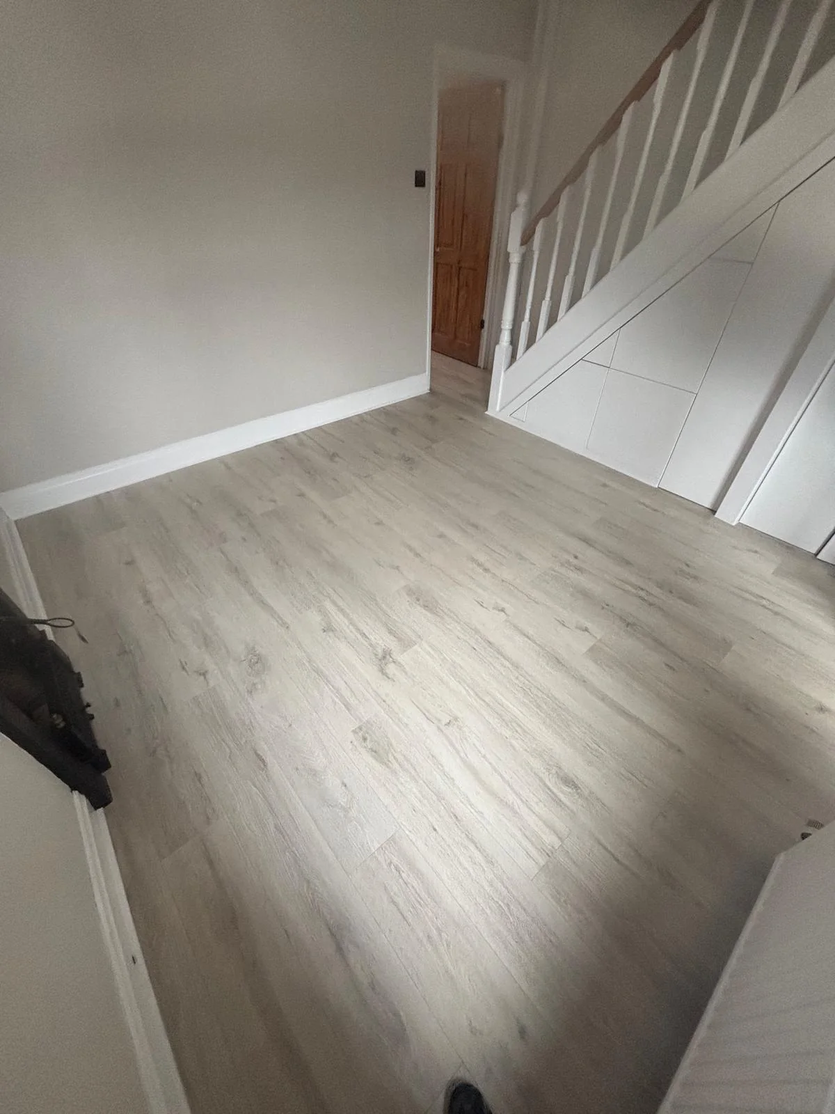 Pale wood-effect flooring beside a staircase